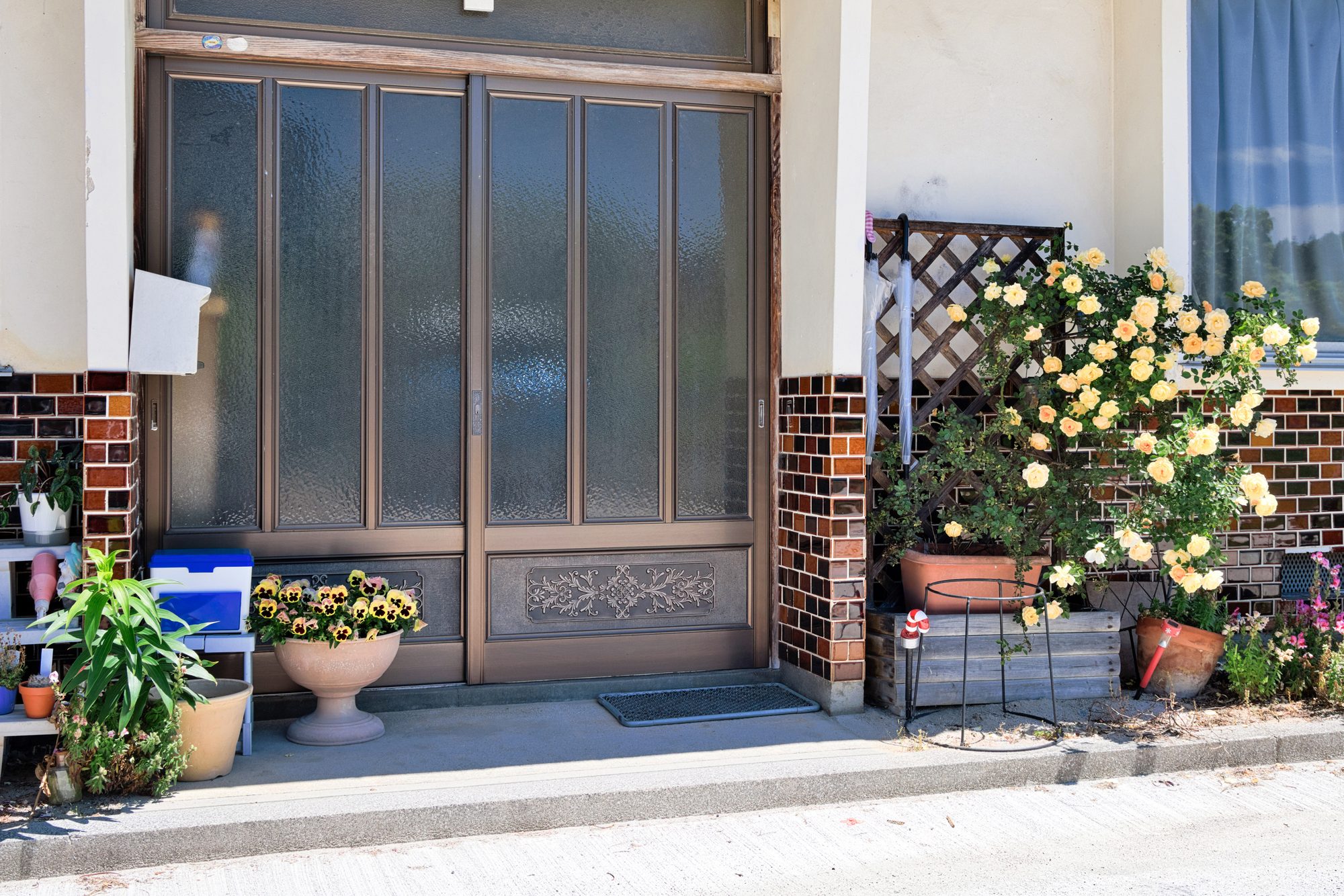 引き戸の玄関と、鉢植えの花が置かれた住まいの入口